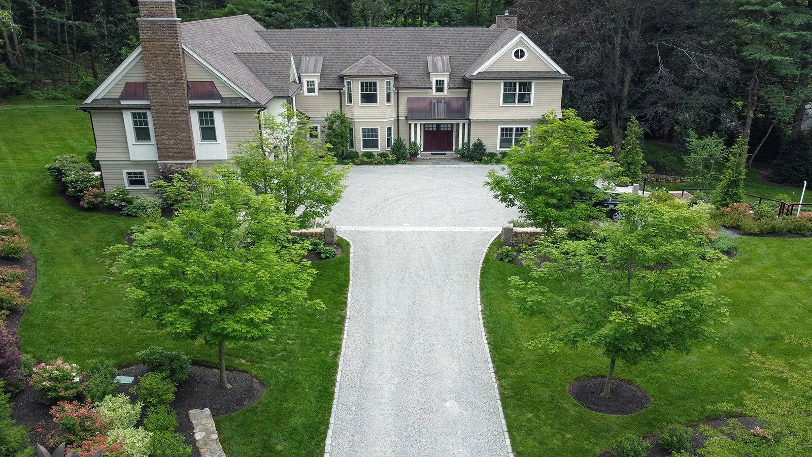 Wide gravel driveway curving up to a large shingled house