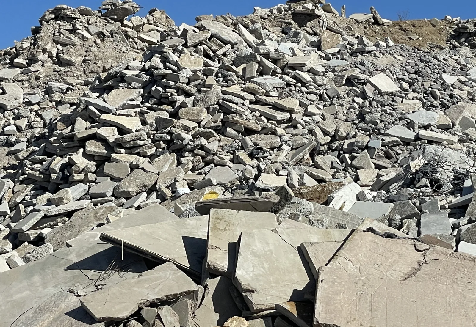 Pile of broken concrete slabs stacked against a blue sky