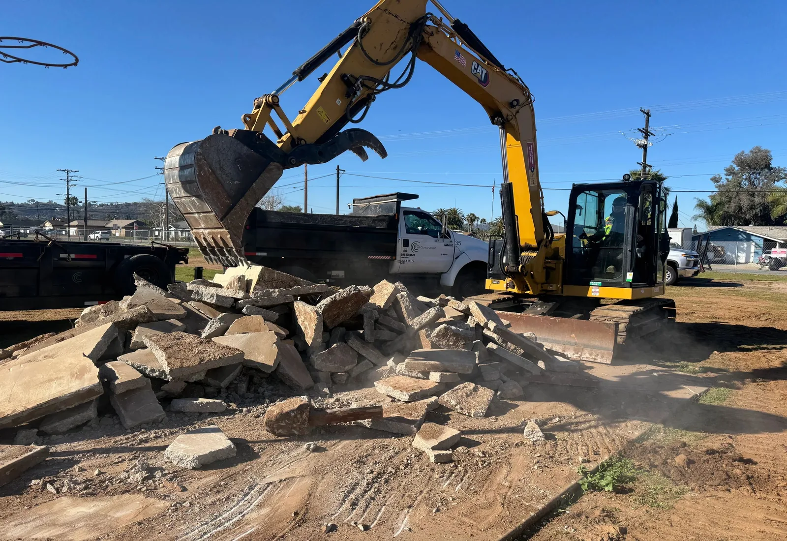 Excavator with a thumb breaking out and stacking slabs of old concrete