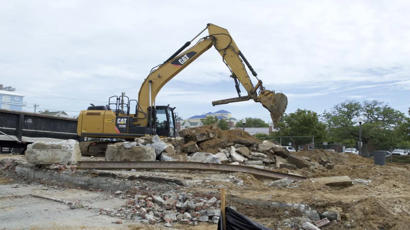 Excavator working a pile of broken concrete and foundation rubble