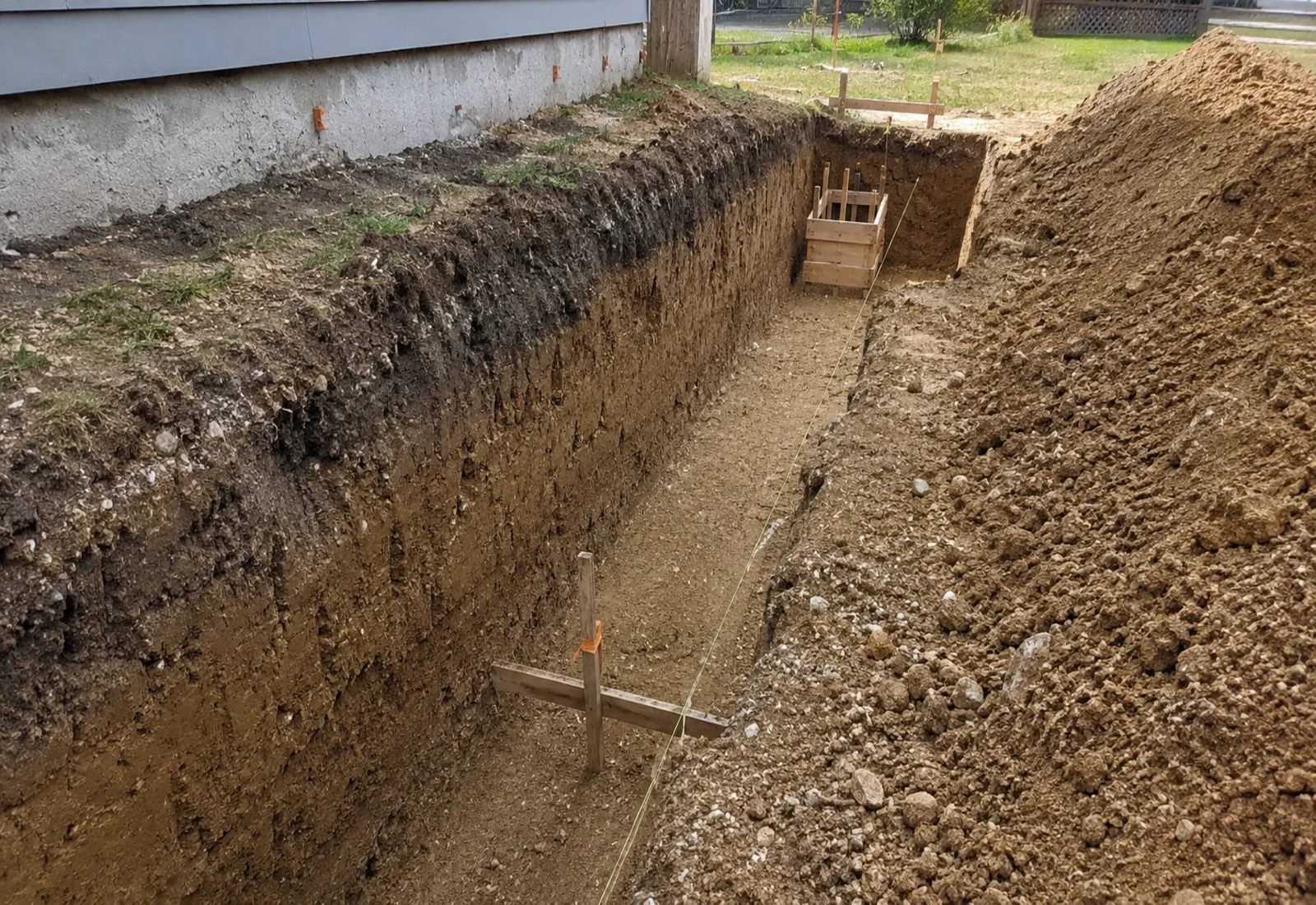 Dug foundation trench with clean vertical walls and batter boards set over it