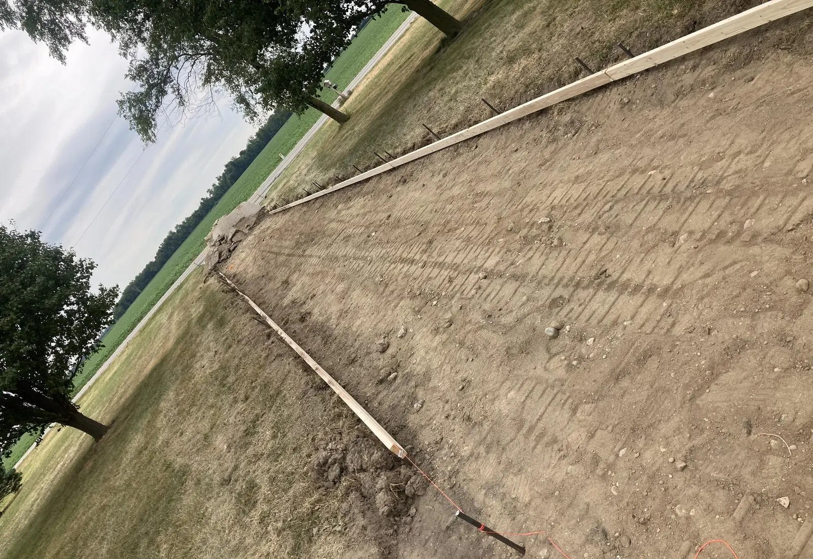 Freshly cut driveway subgrade staked out along a wood form