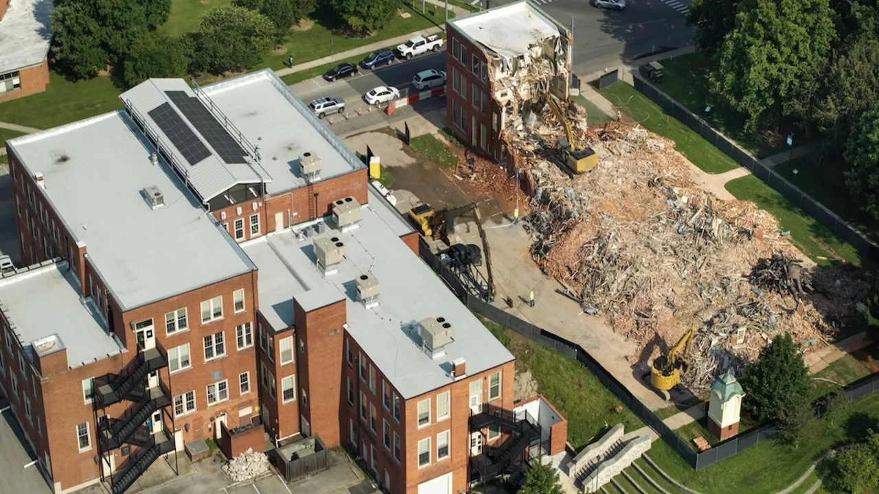 Aerial view of a brick building being demolished beside a sorted rubble pile